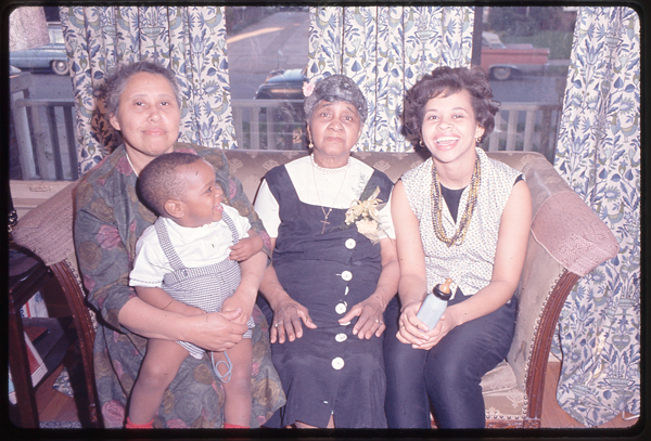Four generations. Baby Thomas sits on his grandmother, Joella’s lap, his mother Rudean (r), and his great grandmother Evelyn (c). 1960s, ca.