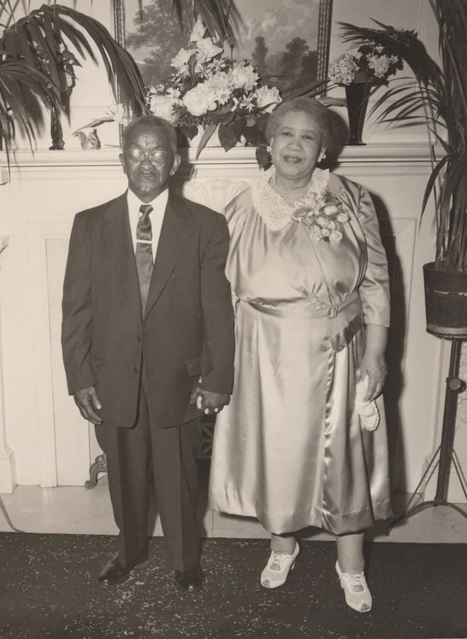 Man and Woman stand side by side in front of a mantle. Black and White photo