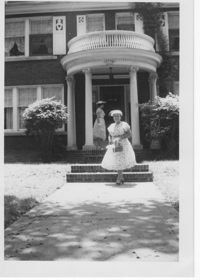 Mary Walton stands in front of their house on the walled way. Surrounded by greenery