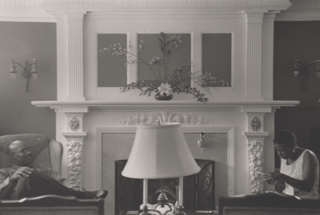Ronald and Michelle sit opposite each other, the fireplace between them. Black and White photo