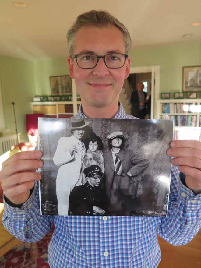 Viktor Witowski holds up a print photo of his family playing dress up. Black and White photo.