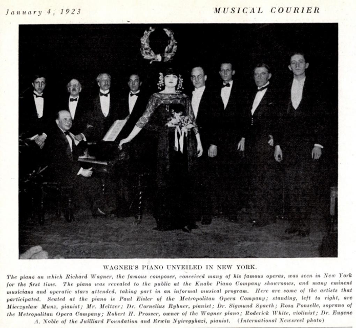 Paul sits at a piano surrounded by eight men in tuxedos and Rosa Ponselle resting her hand on the piano